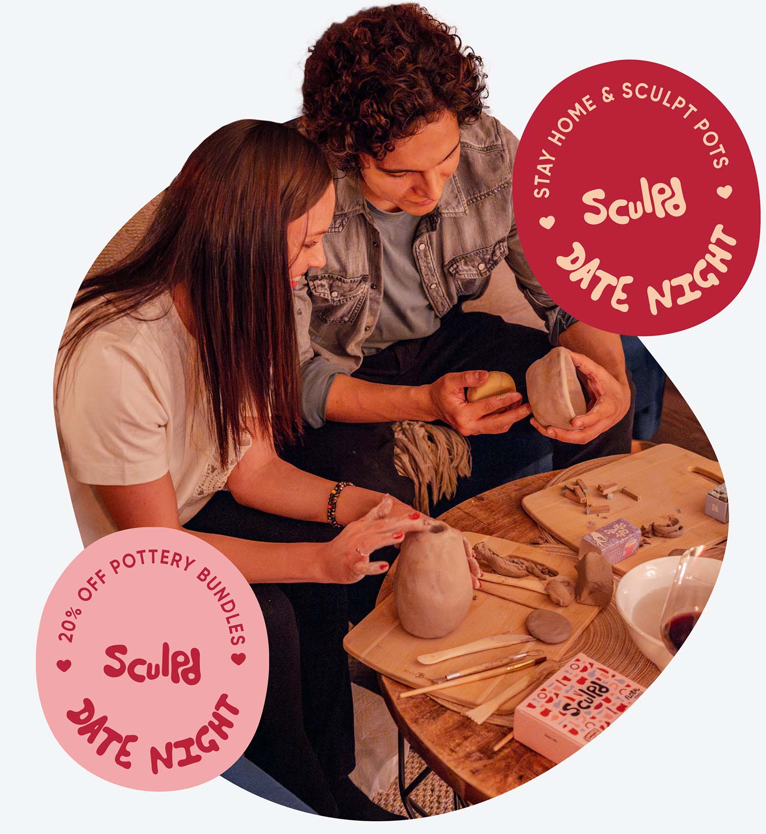 A couple enjoys a cozy pottery date night setup featuring Sculpd Pottery Kits, candles, red roses in a vase, and sculpting tools arranged on wooden boards, creating a warm and romantic ambiance
