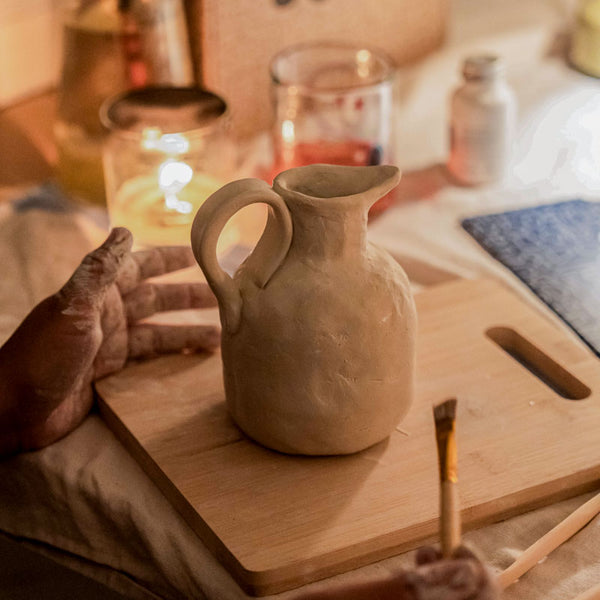 Sculpd Pottery Kit pot being varnished on a table with candle-lit background
